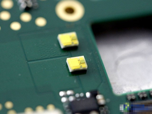 这两个小黄点是什么东西?它们正是联想手机A8的双闪光灯。可能有人第一次见到闪光灯的内部样子。你应该还没有忘记前面中框闪光灯灯罩的图片吧,把灯罩加上之后,就成了我们平常看到的闪光灯整体。